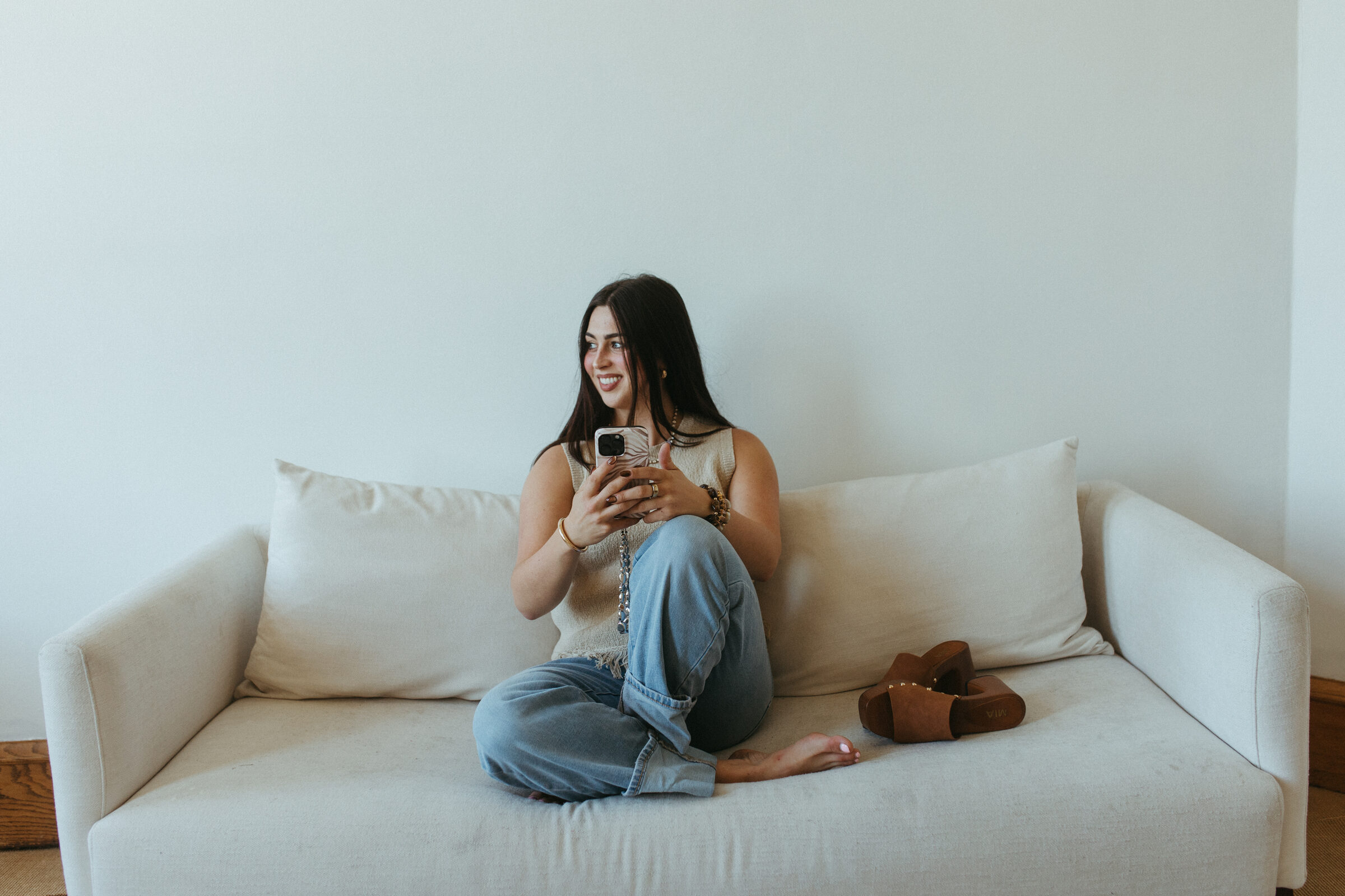 Morgan Bartow of Mosie Kate Kollective sitting on a cream sofa with her phone