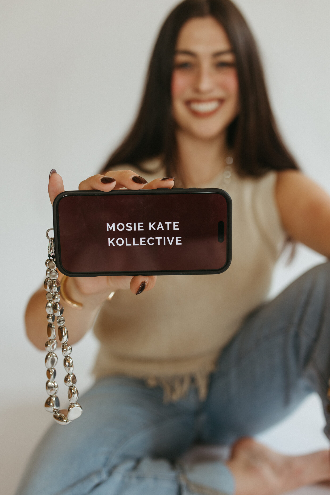Morgan holding up a phone showing the Mosie Kate Kollective logo